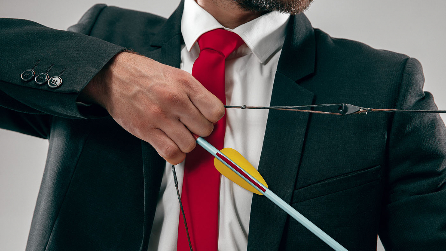 Businessman aiming at target with bow and arrow isolated on gray studio background. The business, goal, challenge, competition, achievement, purpose, victory, win, clarity, winner and success concept