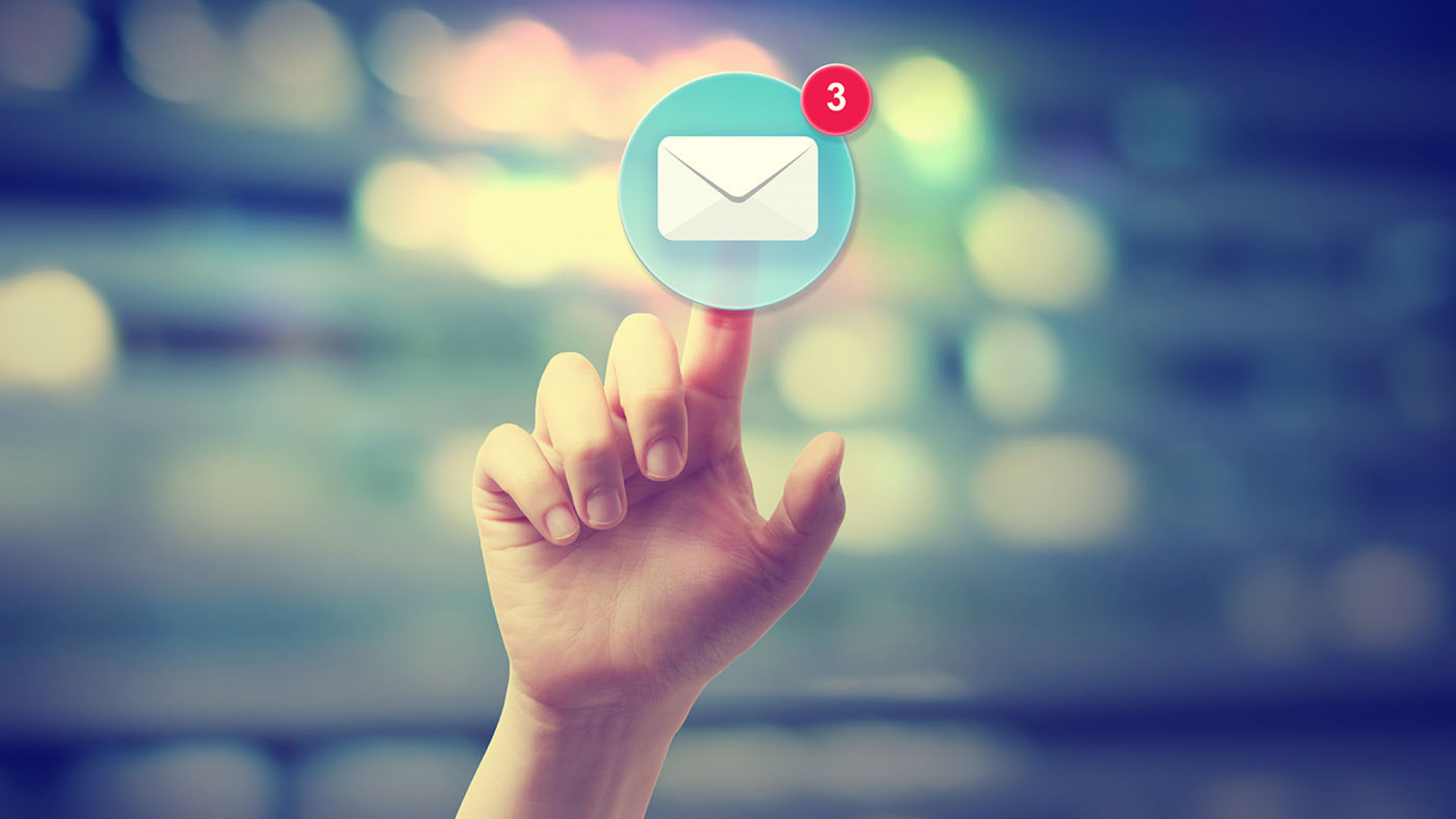 Hand pressing an email icon on blurred cityscape background